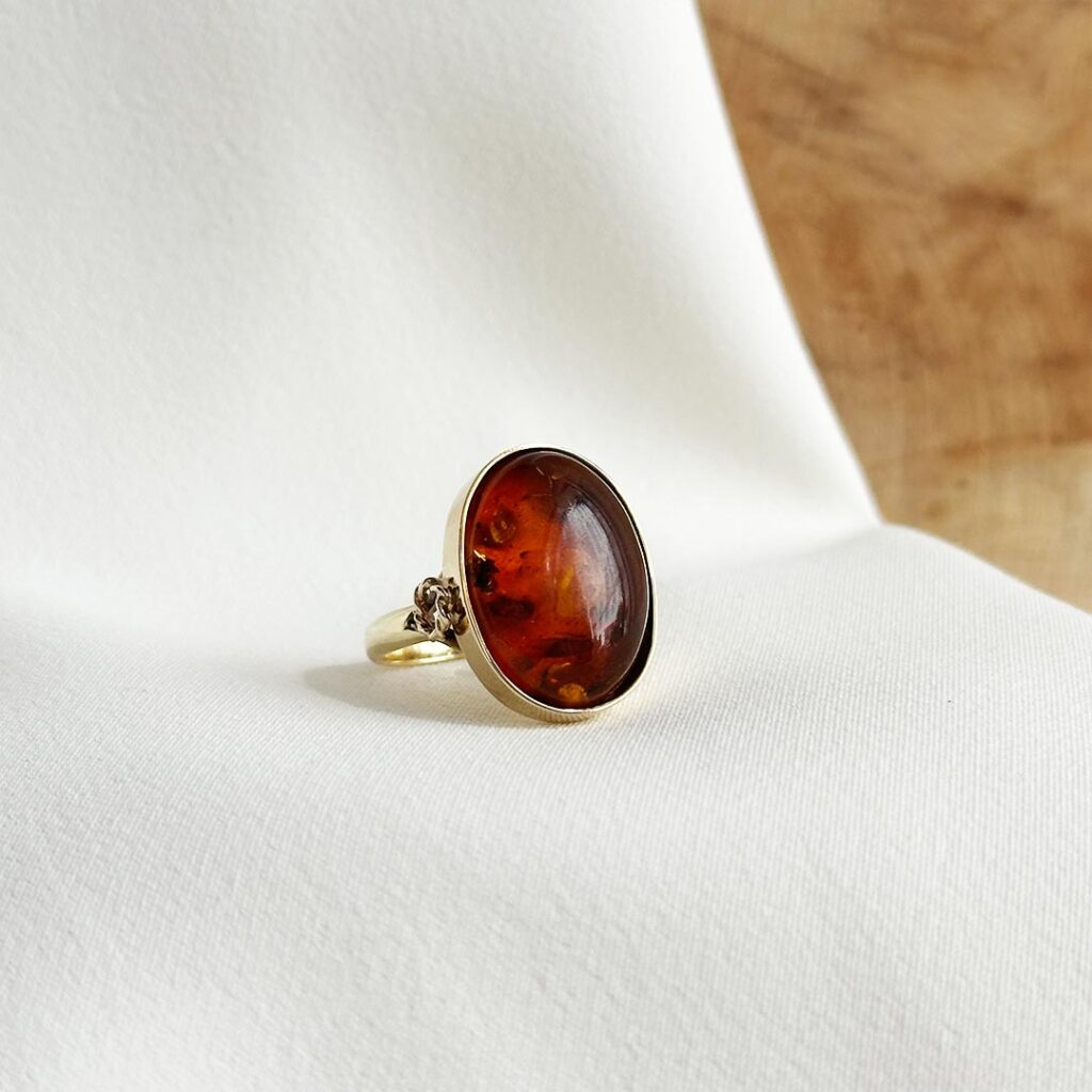 Ring aus 585 Gelbgold mit Bernstein und zartem Kordelkreis-Detail an der Seite, in eleganter Nahaufnahme präsentiert.