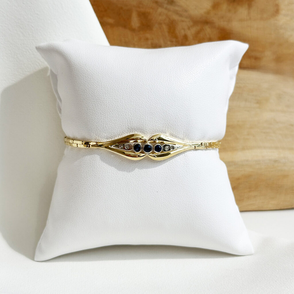 Damenarmband aus 750er Gelbgold mit Saphiren und Diamanten, elegant auf einem Schmuckpolster präsentiert.