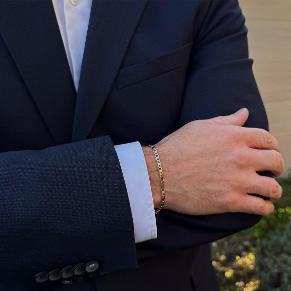 Herrenarmband aus Gelbgold 585 im Broadkette-Muster, getragen am Handgelenk eines Mannes in einem Anzug. Frontansicht.