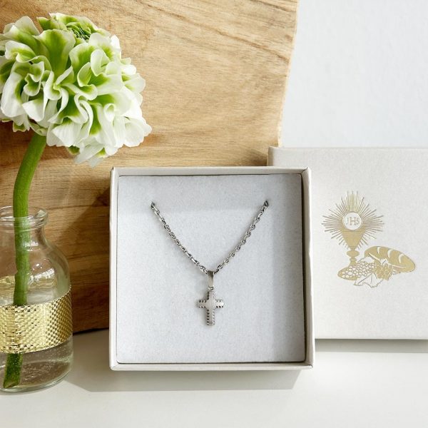 Weißgoldkreuz mit facettiertem Rand aus 585 Weißgold auf Weißgoldkreuz in Schmuckverpackung vor einer eleganten Holzwand. Artikelnummer 6402