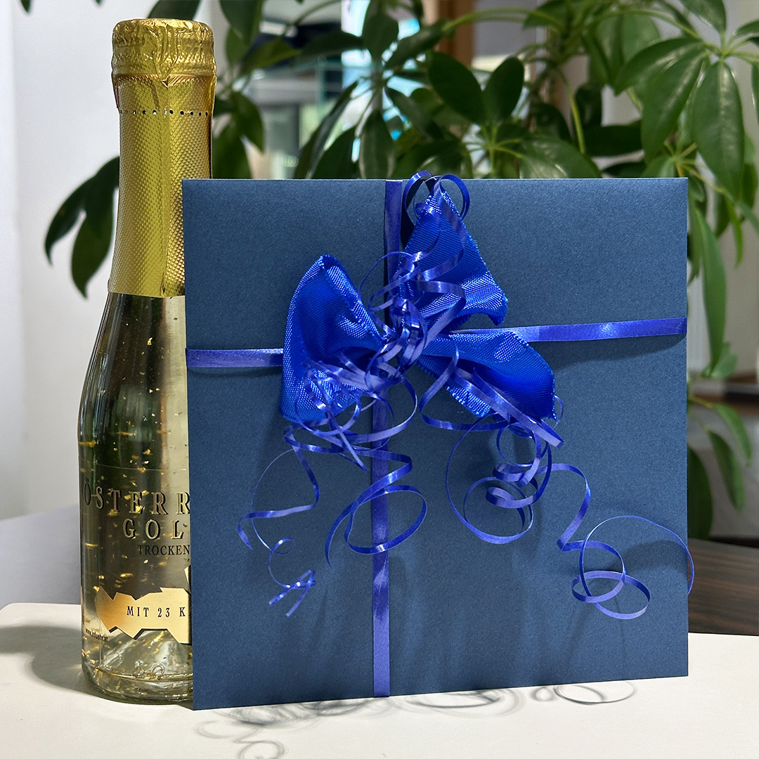 Geschenkgutschein verpackt mit blauer Schleife und Sektflasche