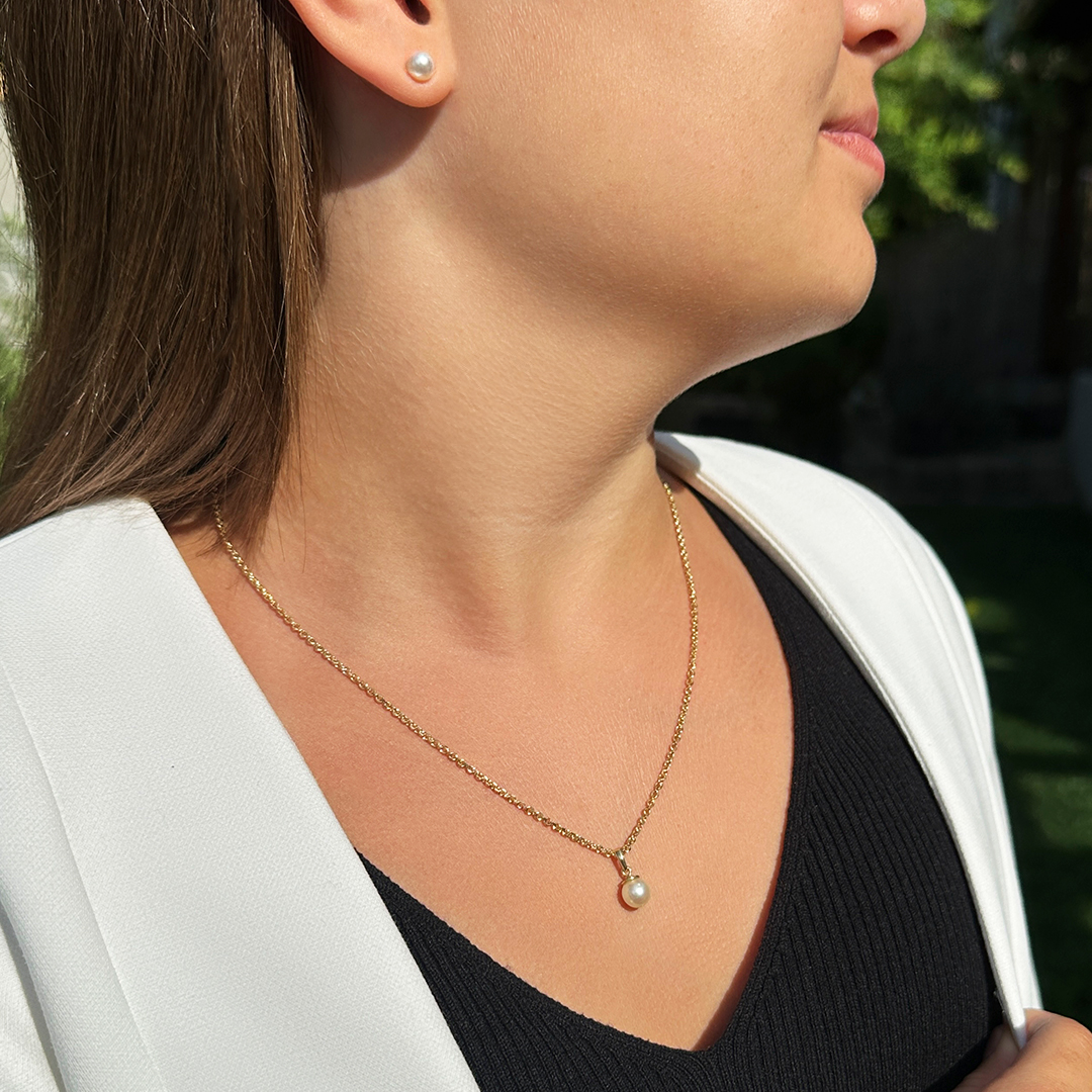 Kinderschmuck aus Gold ein Kind trägt eine Kinderkette mit Perlenanhänger