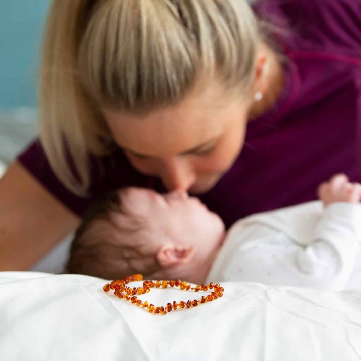 beautiful blond mother with her 3 month old baby wearing a amber necklace