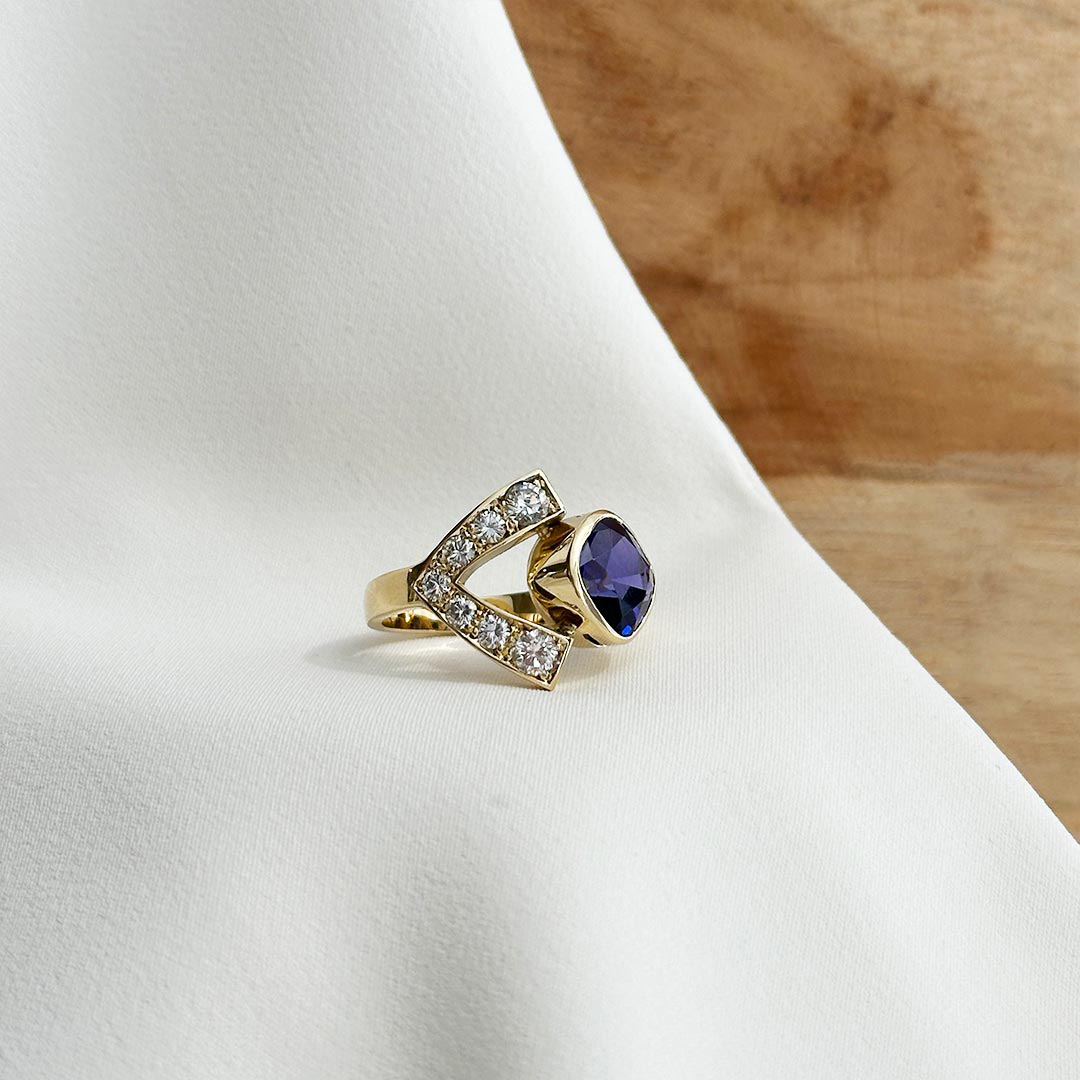 Schmuckanfertigung Ring mit Diamanten und Edelstein aus 585 Gelbgold fotografiert auf elegantem Stoff.