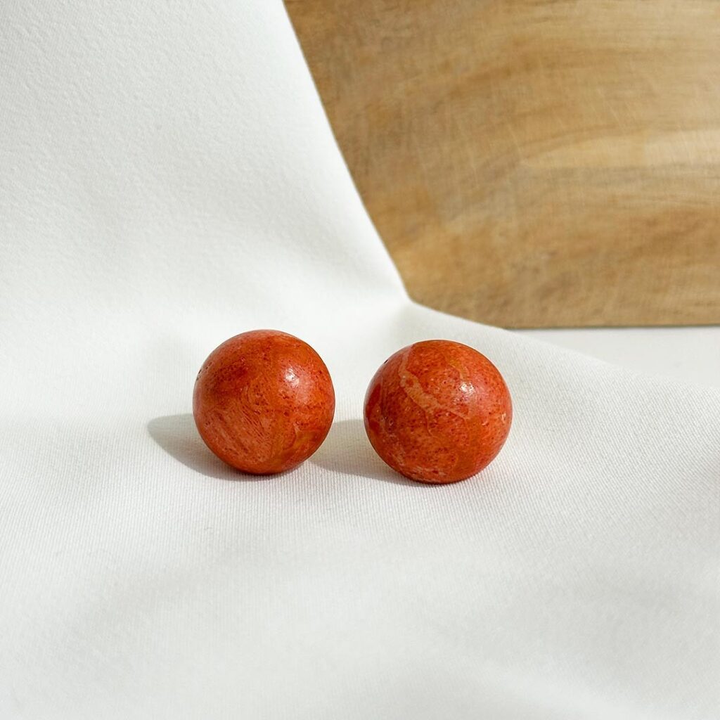 Ohrstecker aus Schaumkoralle mit halbkugelförmiger Koralle in kräftigem Rot, 18mm Durchmesser, auf feiner Goldplatte, frontal fotografiert.