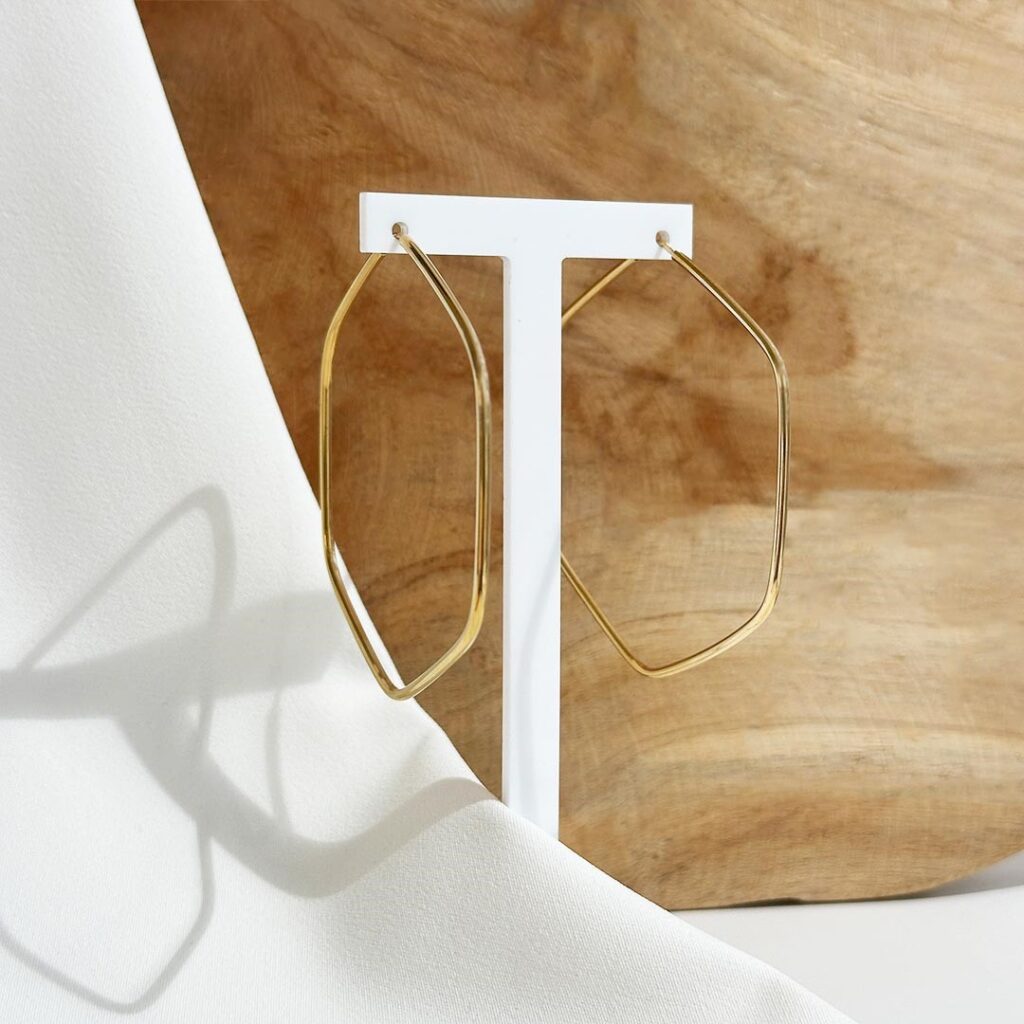 Hexagonale Creolen aus 585er Gelbgold, elegante Nahaufnahme auf Schmuckaufsteller, Fokus auf die präzise Linienführung und den warmen Goldglanz