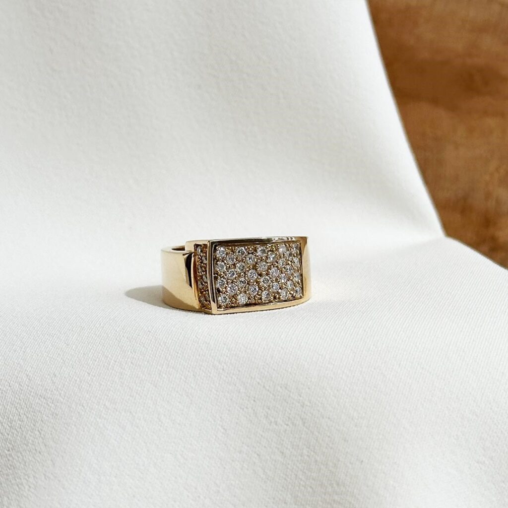 Markanter Ring aus 585er Gelbgold mit funkelndem Brillantbesatz und hochglanzpolierter Oberfläche, breite Form flach gearbeitet, in eleganter Nahaufnahme präsentiert.
