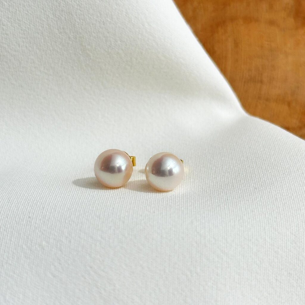 Akoya-Perlenohrstecker aus 585 Gelbgold mit roséfarben schimmernden 7,5–8mm Perlen in frontaler Ansicht.