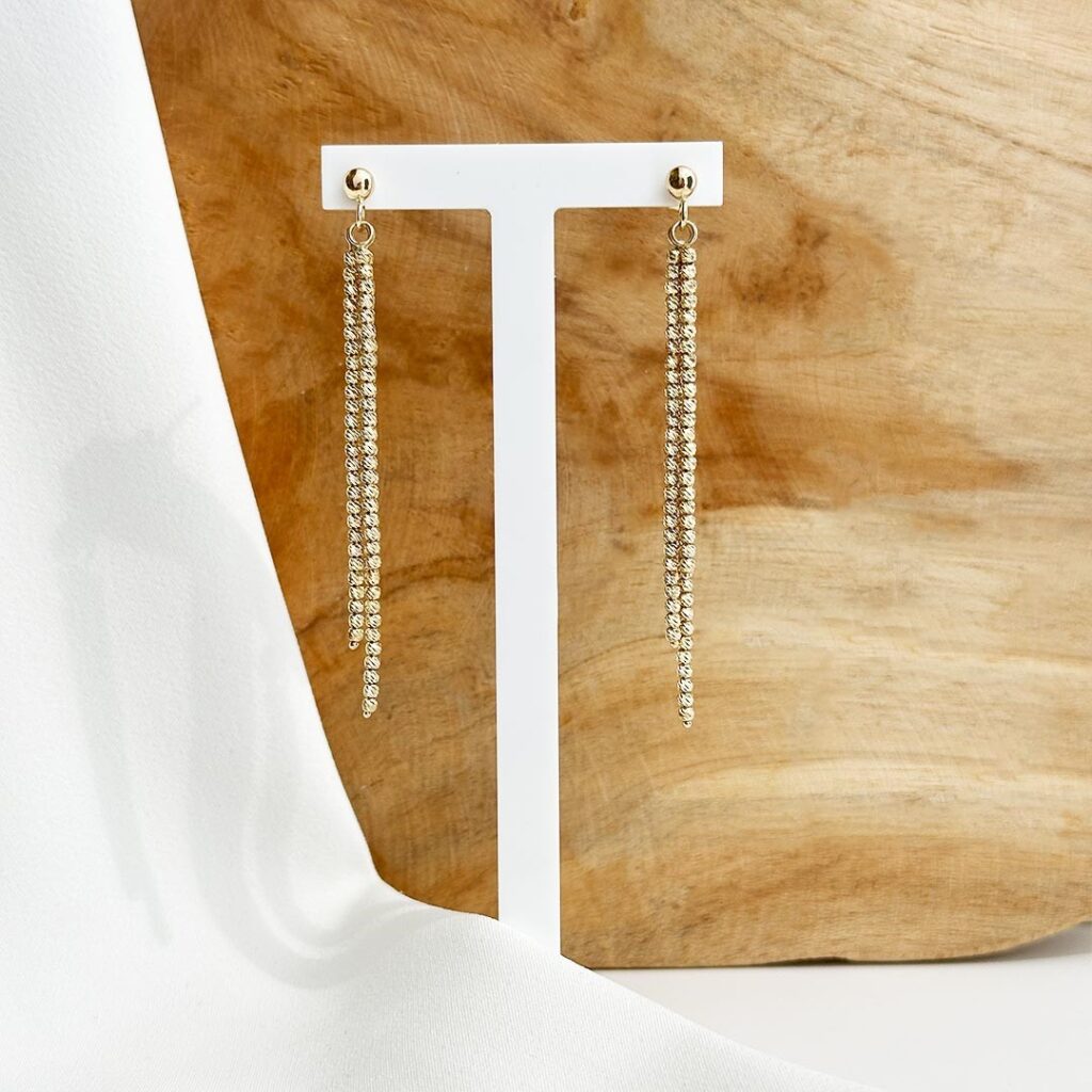 Lange 7cm Ohrstecker aus 585er Gelbgold mit drei feinen, facettierten Kettensträngen, die sanft schwingen und einen eleganten, lichtreflektierenden Schimmer erzeugen.