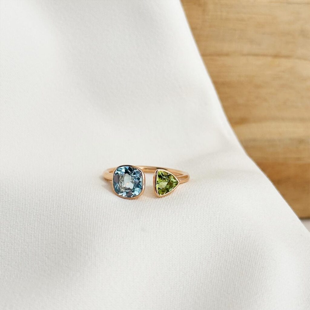 Roségold-Ring mit offenem Design, besetzt mit Blautopas und Peridot in verschiedenen Schliffformen, elegant präsentiert.