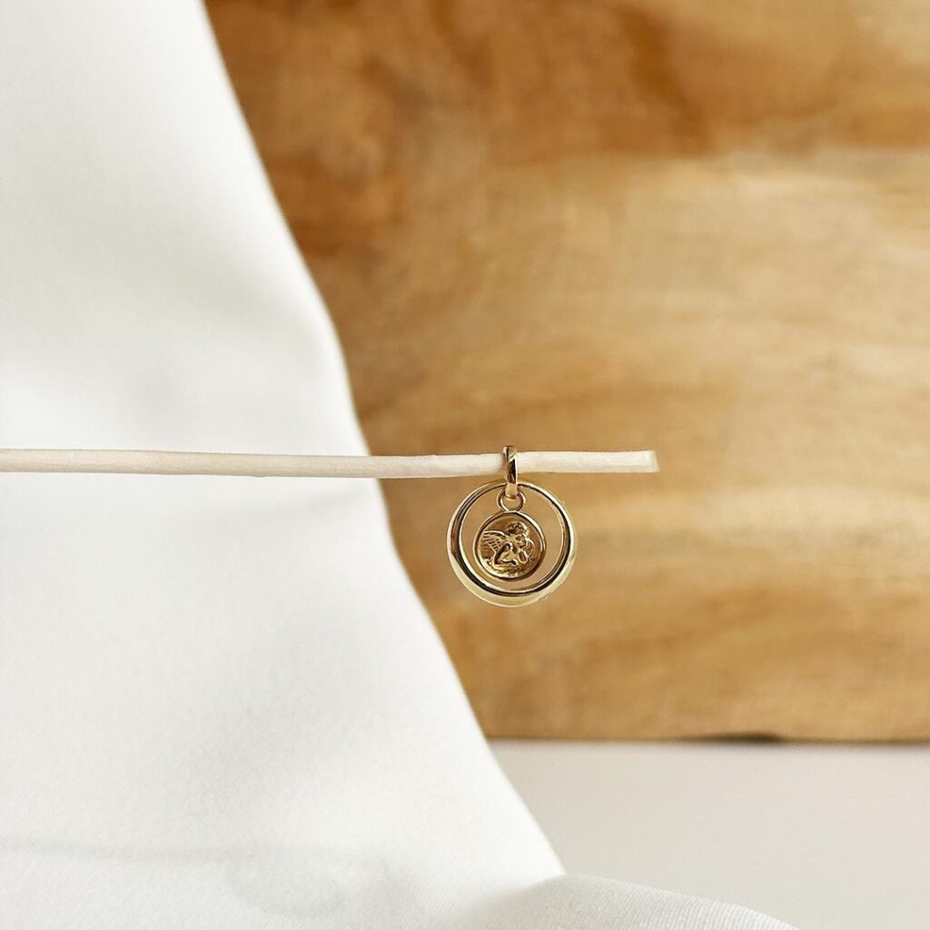 Nahaufnahme eines liebevoll gestalteten Anhängers aus 585er Gelbgold, bestehend aus einem klassischen Taufring, der einen kleinen, zarten Schutzengel umrahmt – ein symbolisches Schmuckstück für Liebe, Geborgenheit und Schutz.