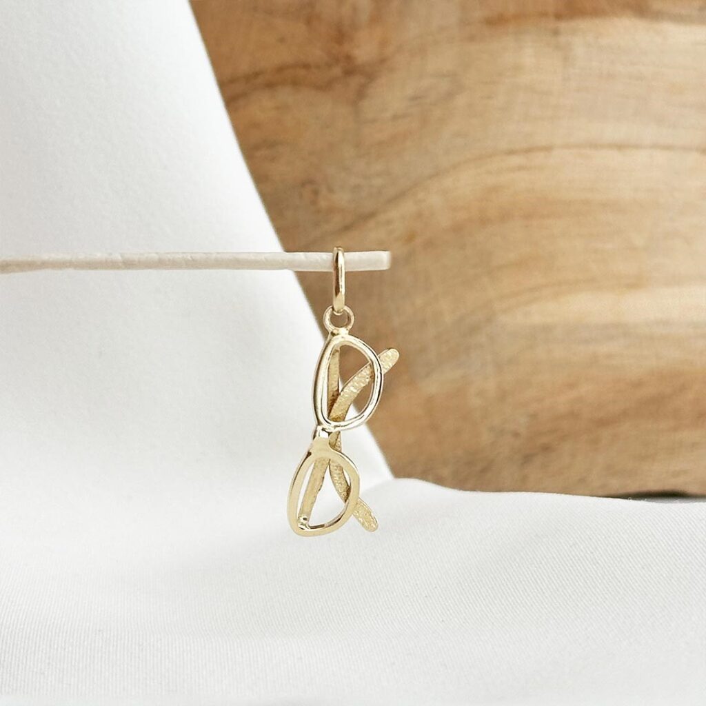 Brillenanhänger aus 585er Gelbgold in eleganter Nahaufnahme, stilisiert und klar gearbeitet; feine Konturen, polierte Oberfläche und detailreiche Form, präsentiert als charmantes Schmuckelement für Bettelarmband oder Halskette.