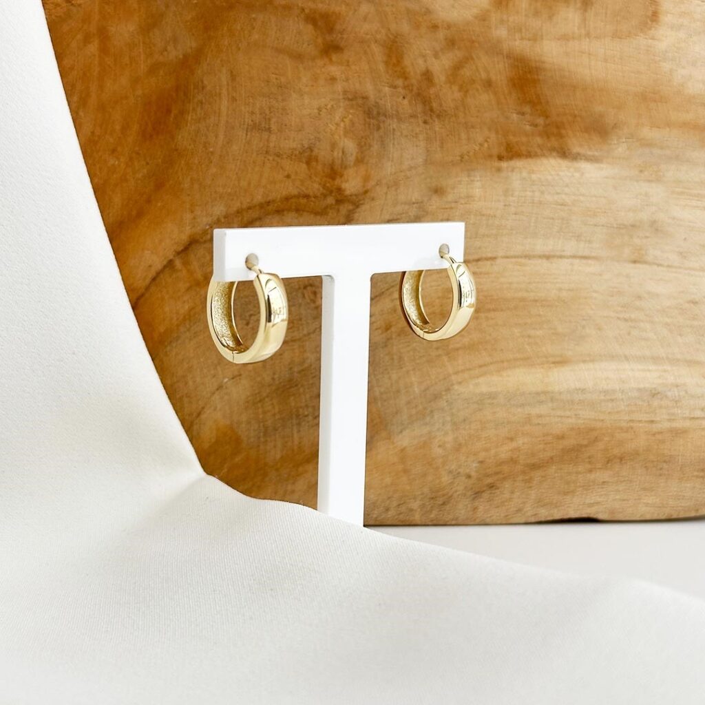 Klassische Creolen aus 585 Gelbgold mit 16mm Durchmesser und 4mm Breite, polierte Oberfläche, in eleganter Nahaufnahme vor einer Holzwand seitlich fotografiert.