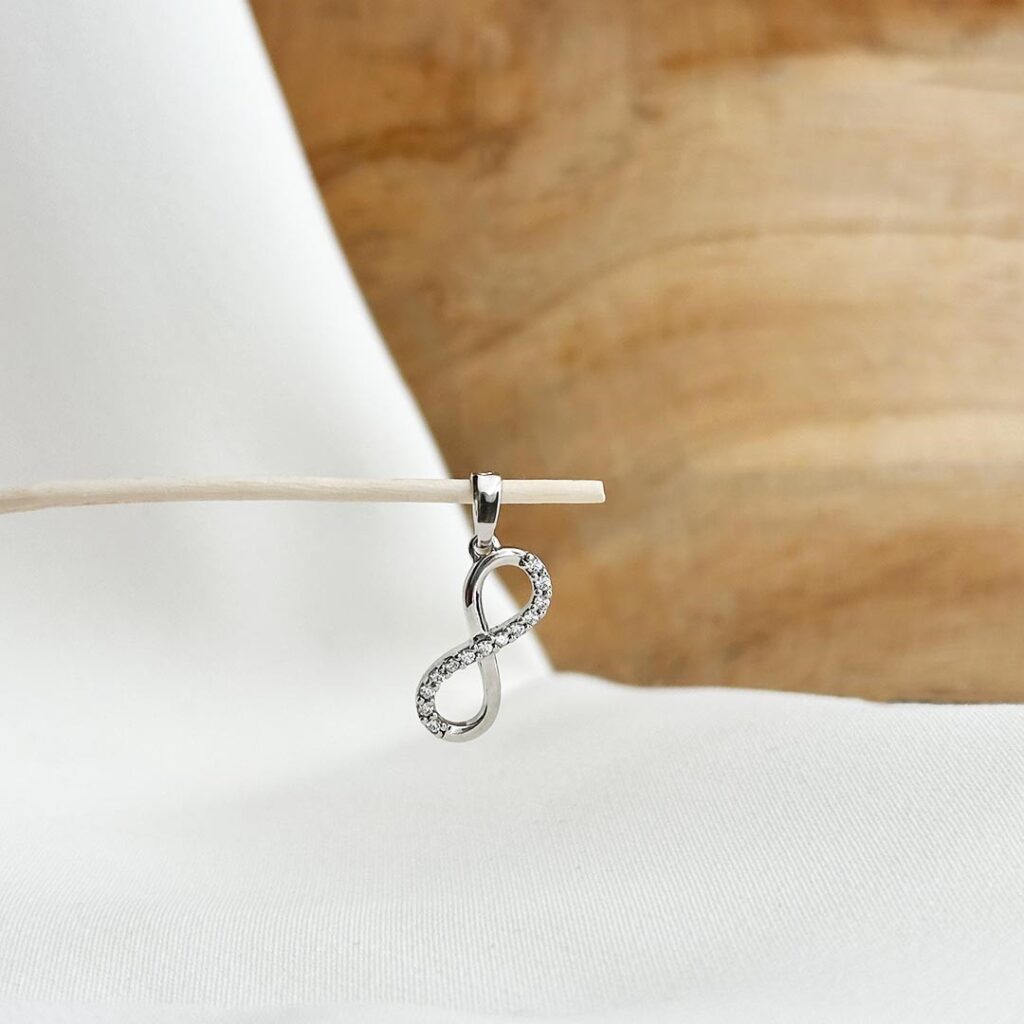 Infinity-Anhänger aus 585 Weißgold mit funkelnden Zirkonia-Steinen, klar geschwungene Form, in eleganter Nahaufnahme präsentiert.