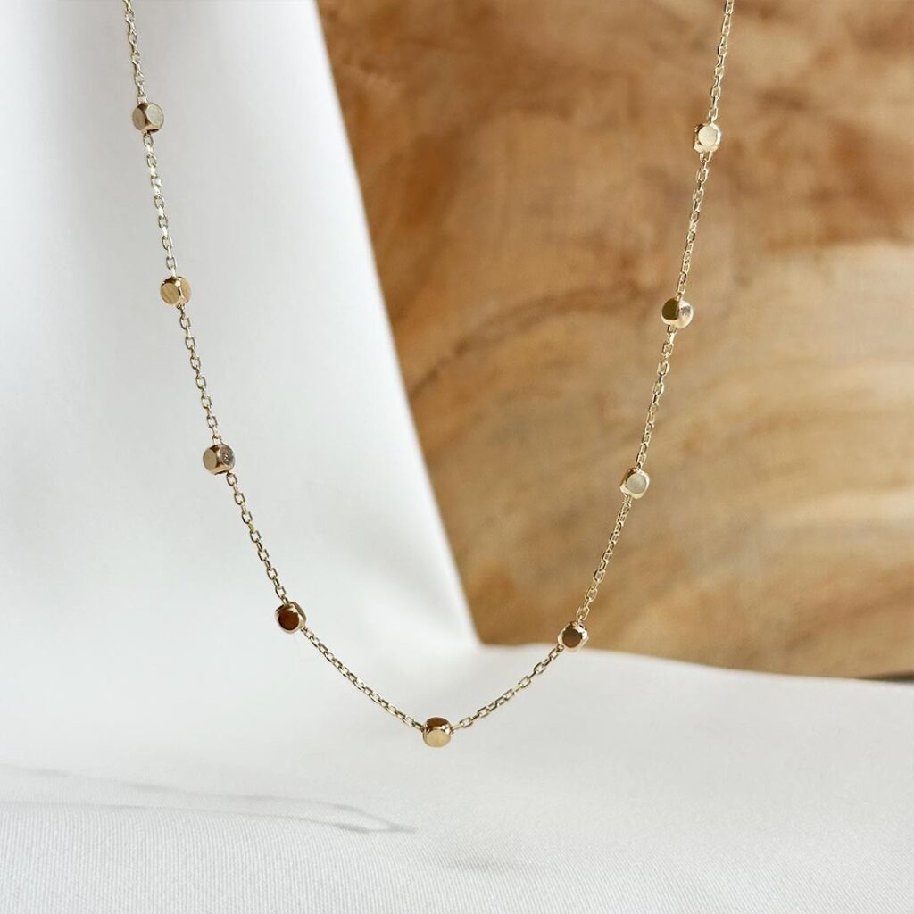 Feine Halskette aus 585er Gelbgold mit kleinen polierten Würfelelementen als glänzende Zwischendetails, 40cm Länge plus 5cm Verlängerung, in eleganter Nahaufnahme gezeigt.