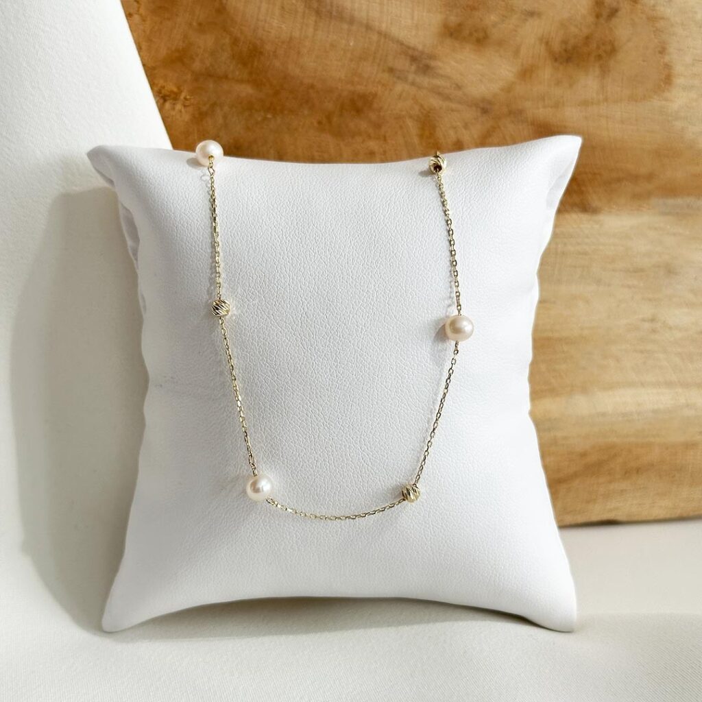 Zartes Collier aus 585er Gelbgold mit facettierten Goldkügelchen und weißen Süßwasserperlen, 45cm Länge plus 3cm Verlängerung, in eleganter Nahaufnahme dargestellt.