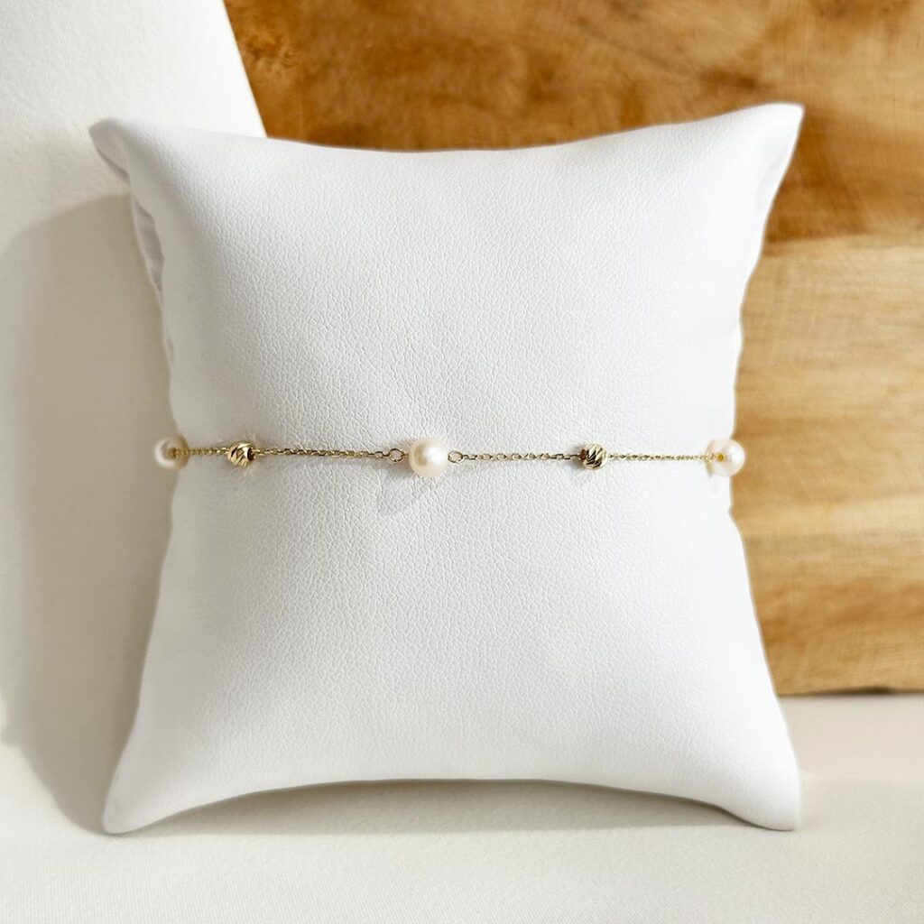 Feines Armband aus 585er Gelbgold mit facettierten Goldkügelchen und weißen Süßwasserperlen in abwechselnder Anordnung, 19cm Länge mit Zwischenöse bei 17cm, in eleganter Nahaufnahme präsentiert.