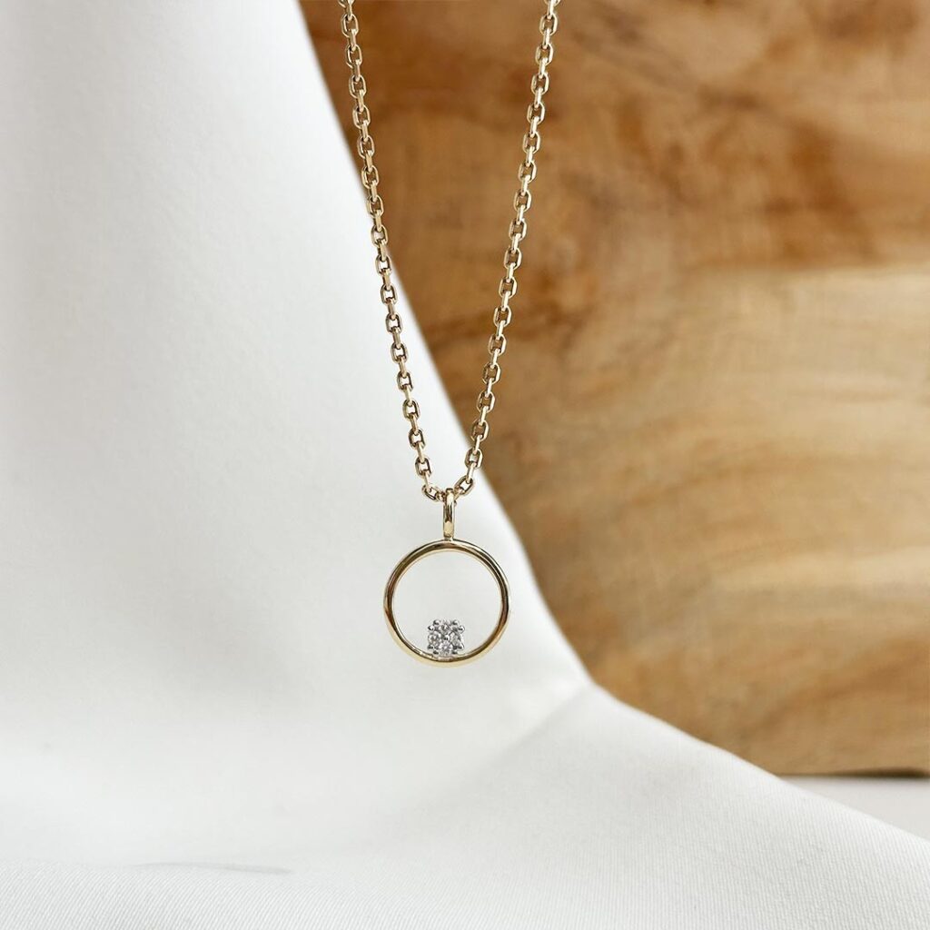 Anhänger aus 585 Gelbgold mit vier dicht aneinandergesetzten Brillanten in Weißgoldfassungen, flache moderne Form auf einer Goldkette, in eleganter Nahaufnahme gezeigt.