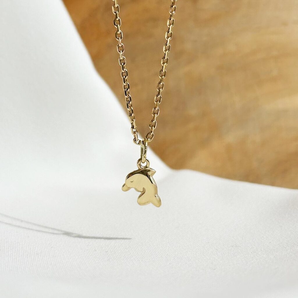 Delfin-Anhänger aus 585er Gelbgold, 11mm groß, liebevoll gestaltet auf einer Goldkette und in eleganter Nahaufnahme präsentiert.