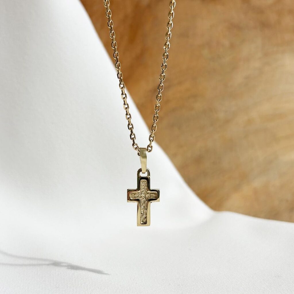 Kreuzanhänger aus 585er Gelbgold, 15mm groß, mit stark strukturierter mittiger Vertiefung und glatter Oberfläche, an einer Goldkette in eleganter Nahaufnahme präsentiert.