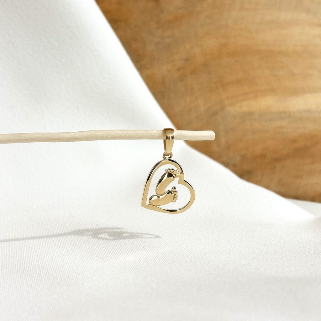 Anhänger aus 585er Gelbgold mit ausgeschnittenem Herz und zarten Babyfüßen im Inneren, 20mm groß, liebevoll in eleganter Nahaufnahme präsentiert.
