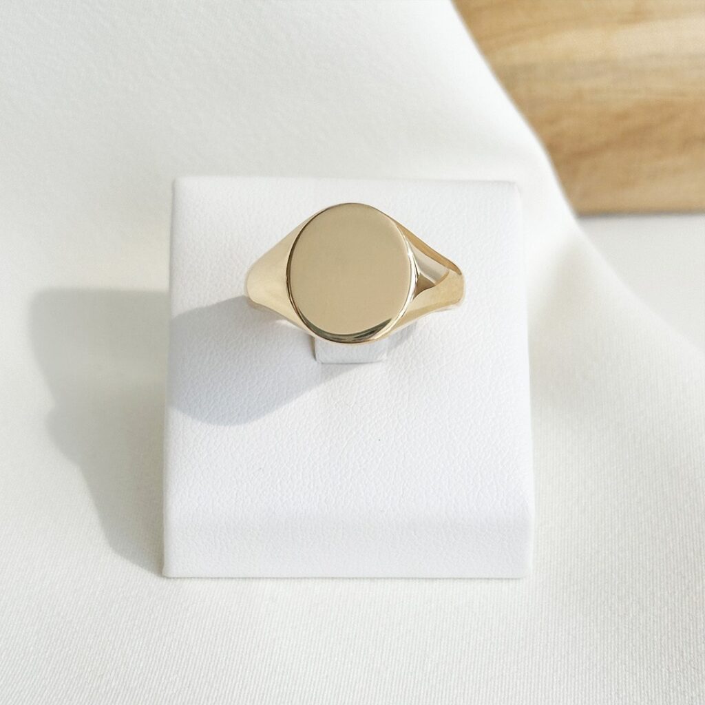 Gravurring aus 750 Gelbgold mit fein abgerundeter 14mm Gravurfläche, in klarer Frontansicht elegant fotografiert.