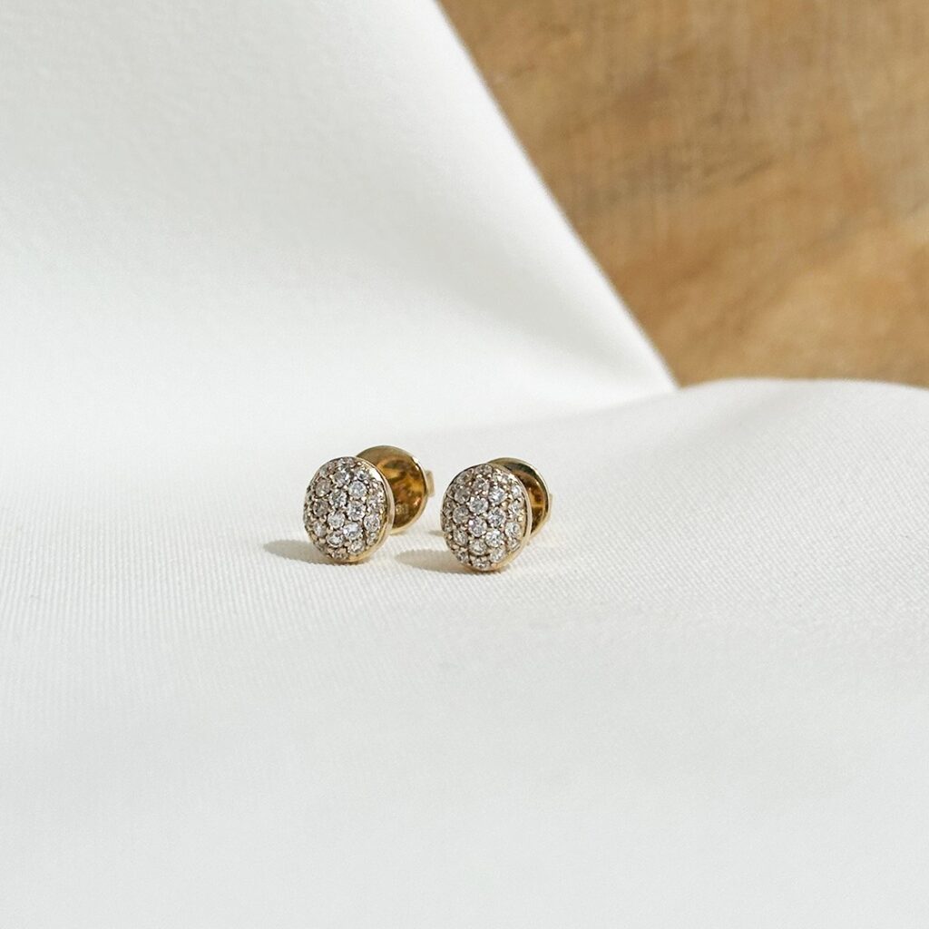 Ovale Ohrstecker aus 585er Gelbgold mit dicht aneinandergesetzten Brillanten von insgesamt 0,36ct., geschlossene Brillanzfläche in leicht erhabener Form, elegant fotografiert.