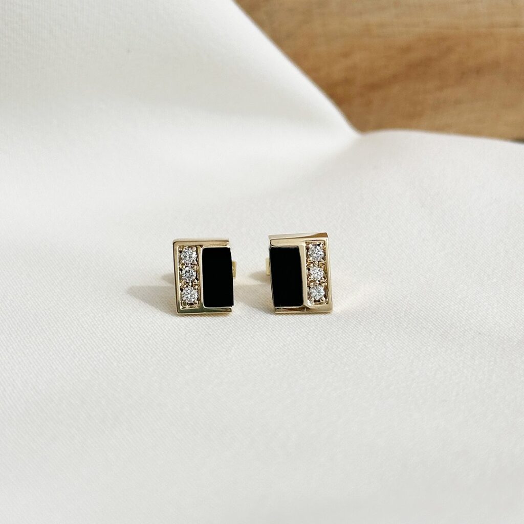 Rechteckige Ohrstecker aus 585er Gelbgold, 9mm groß, mit passgenau eingearbeitetem Onyx auf einer Seite und drei kleinen Brillanten auf der anderen, in eleganter Nahaufnahme präsentiert.