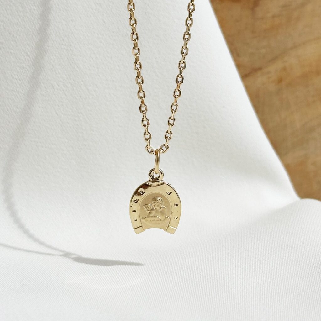 Anhänger aus 585er Gelbgold mit Schutzengel im Hufeisen, 15mm groß, liebevoll gestaltet und in eleganter Nahaufnahme gezeigt.