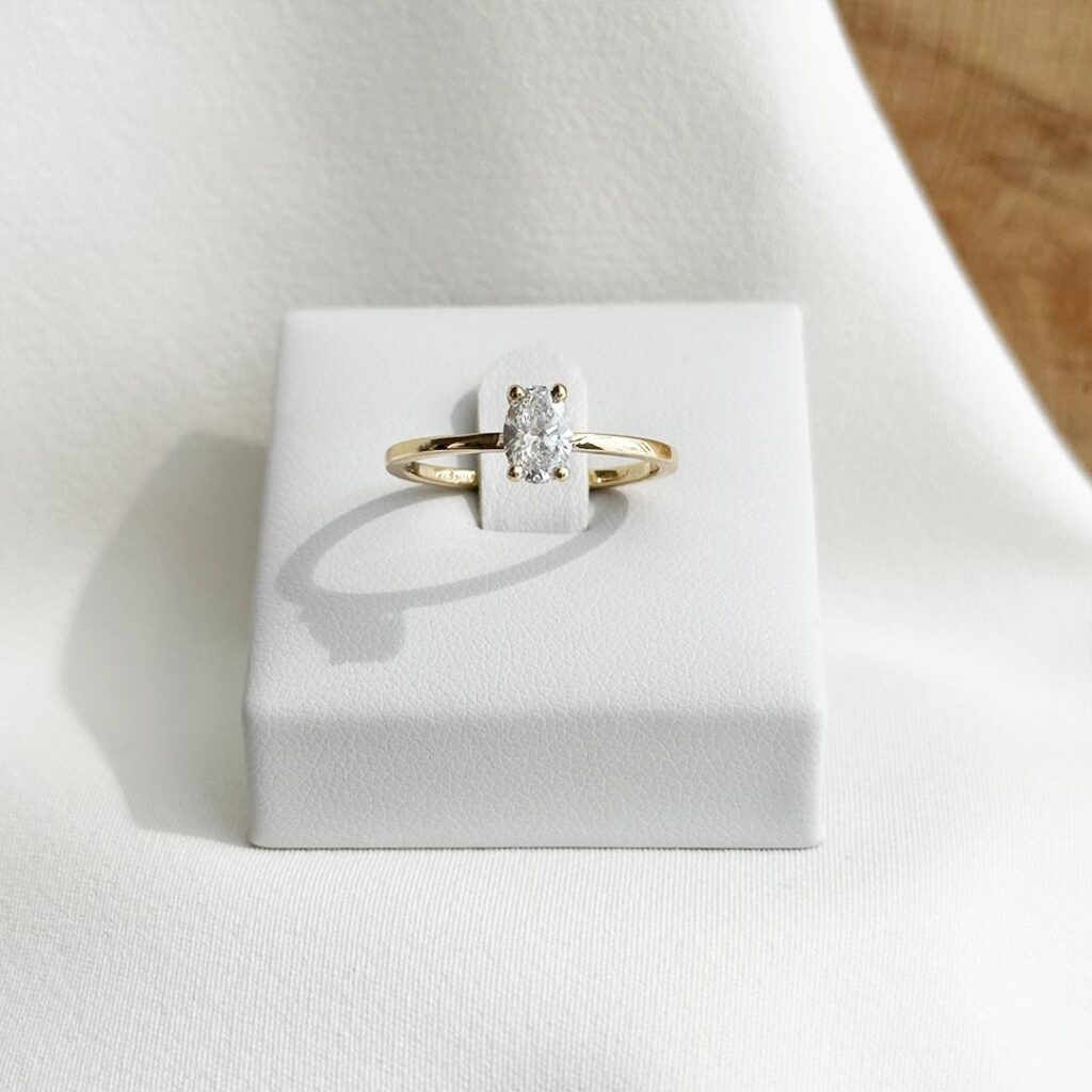Solitaire-Ring aus 750er Gelbgold mit oval geschliffenem 0,50ct. Diamanten, elegant auf einem Ringpodest in klarer Frontansicht präsentiert, mit Fokus auf Stein und Fassung.