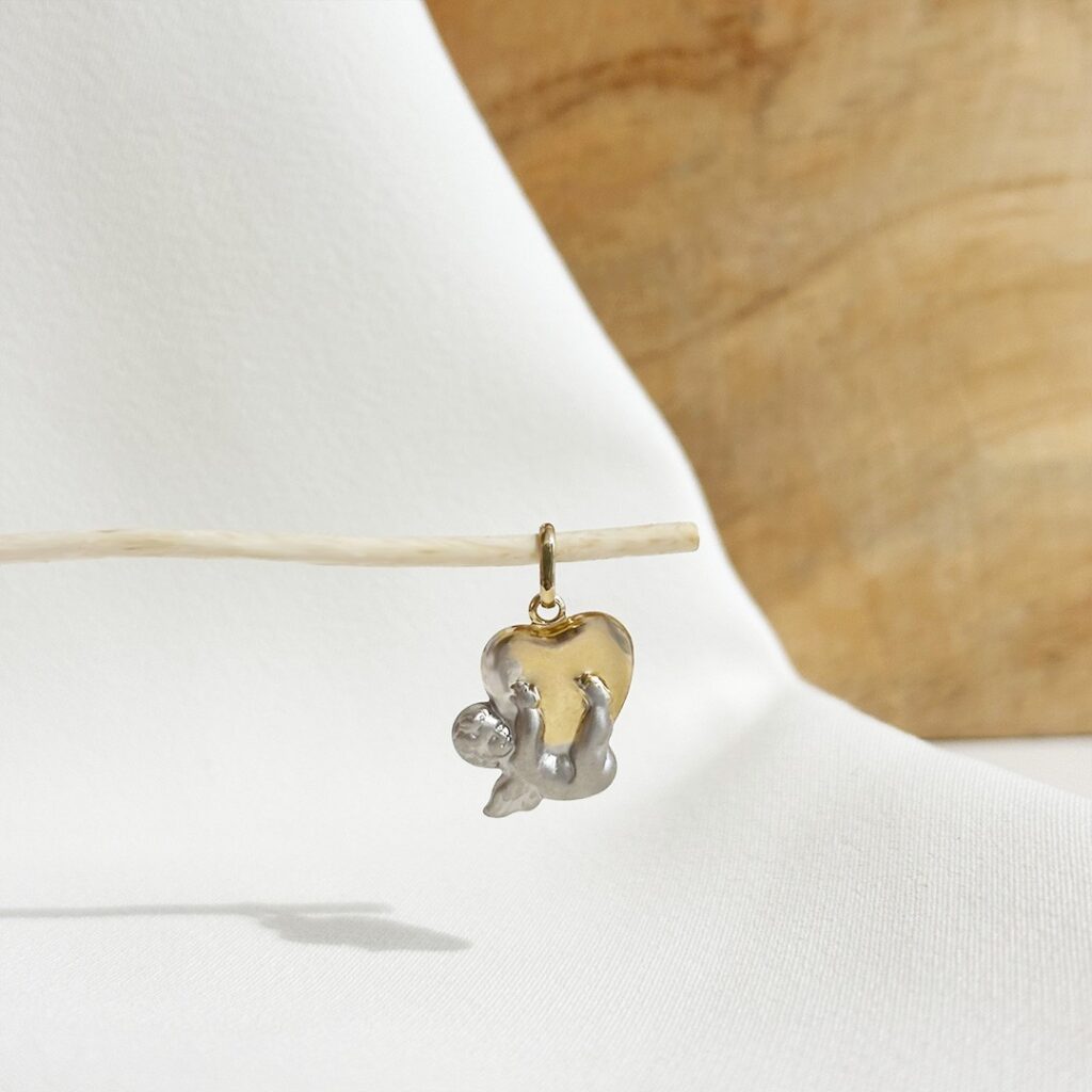 Zweifarbiger Anhänger aus 585 Gold mit gelbgoldenem Herz und kleinem weißgoldenem Schutzengel darunter, in eleganter Nahaufnahme präsentiert.