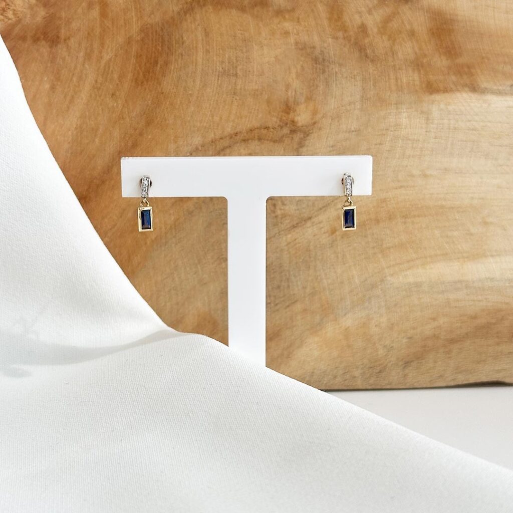 Feine 585er Goldohrringe mit blauem Saphir und kleinen gefassten Diamanten in eleganter Frontansicht, zart und unaufdringlich präsentiert, mit harmonischem Farbkontrast zwischen warmem Gold und tiefem Blau.