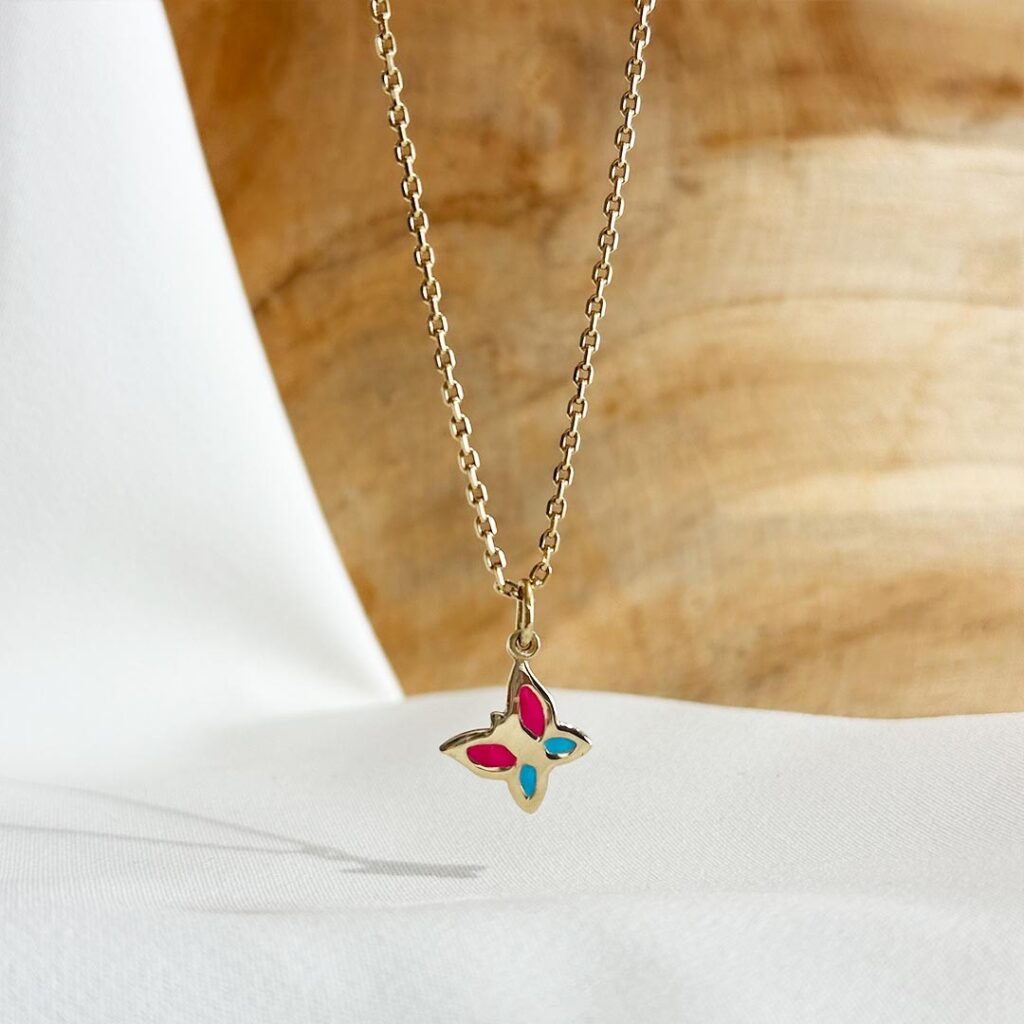 Zarter Schmetterling-Anhänger aus 585er Gelbgold mit blau und rosa lackierten Flügeln, 15mm groß, an einer feinen Goldkette präsentiert; kindgerechtes, farbenfrohes Schmuckstück in liebevoller Nahaufnahme.