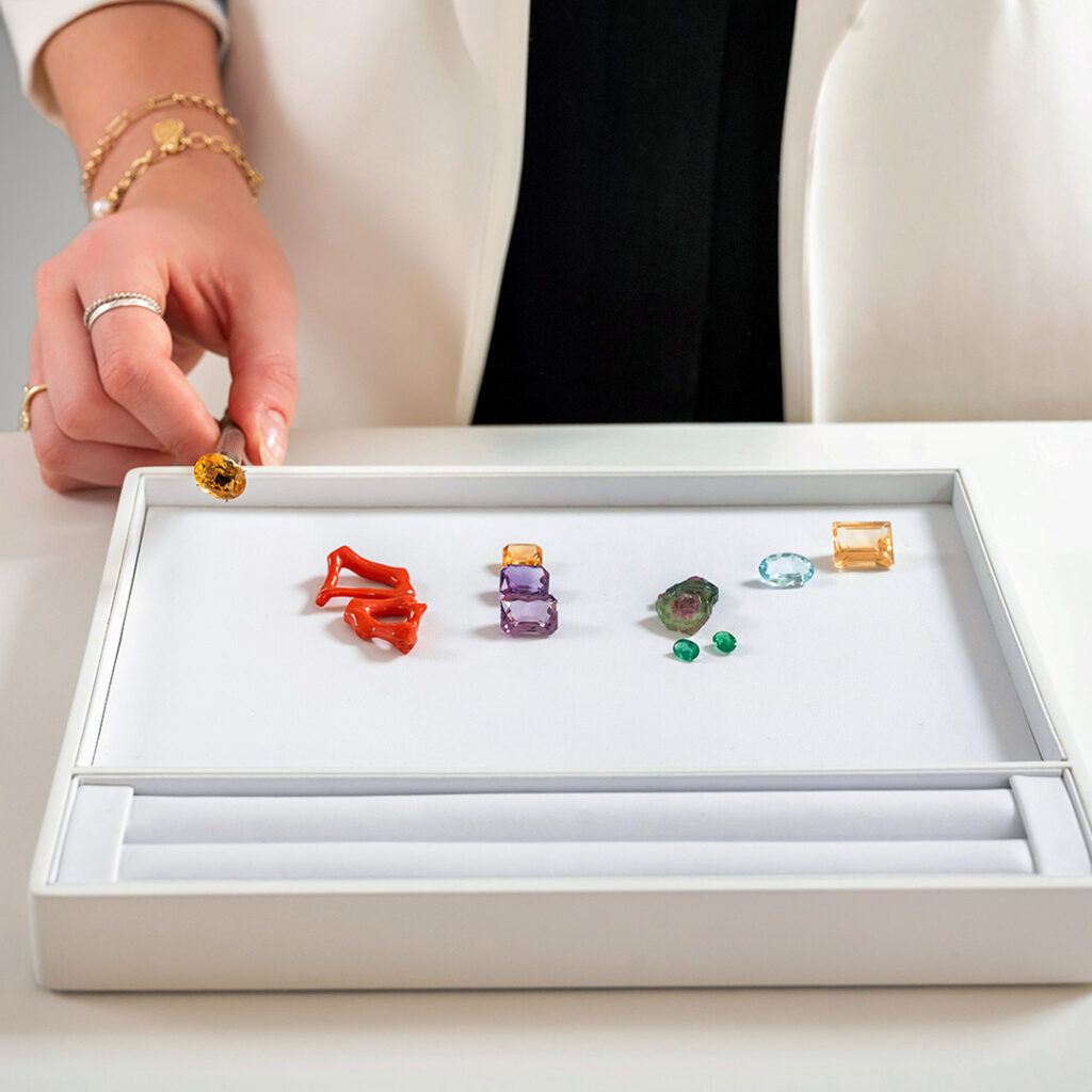 Juwelierin zeigt verschiedene Edelsteine auf weißem Tablett