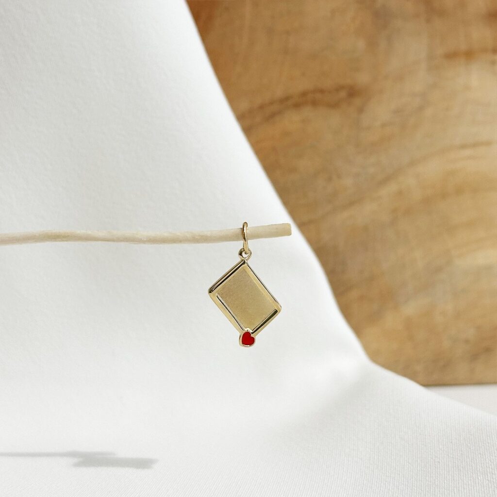 Kleiner Brief-Anhänger aus Gold mit Gravurfläche und rotem Herzdetail, elegante Nahaufnahme als Produktfoto.