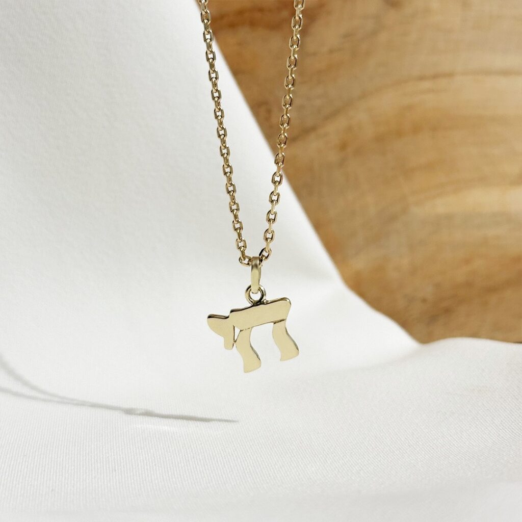 Chai-Anhänger aus 585er Gelbgold, ca.14mm groß, Nahaufnahme hängend an einer Goldkette, Fokus auf die klare Symbolform und die fein polierte Oberfläche.