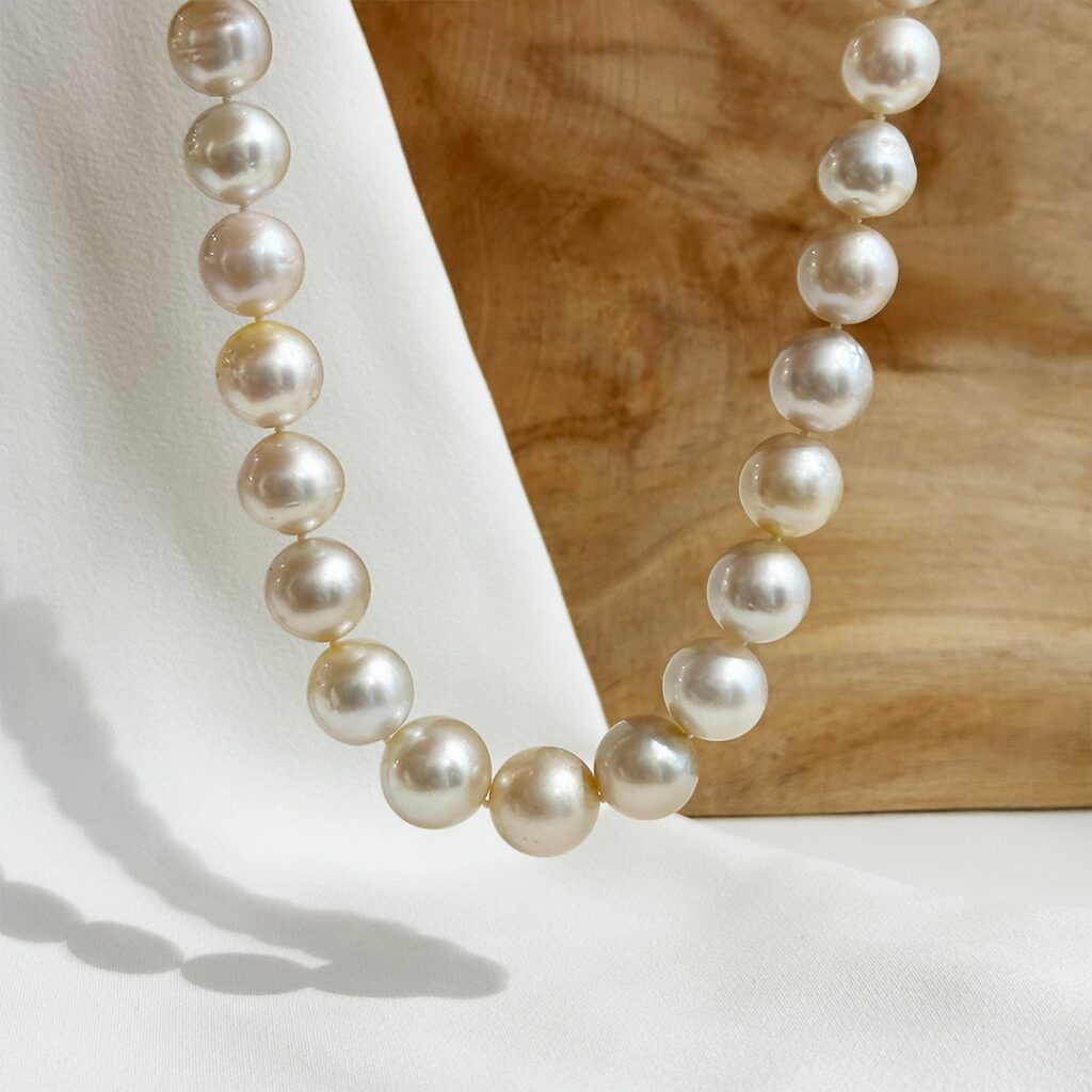 Südseeperlenkette im Verlauf mit großen, weich schimmernden Perlen, hängend präsentiert in eleganter Darstellung.