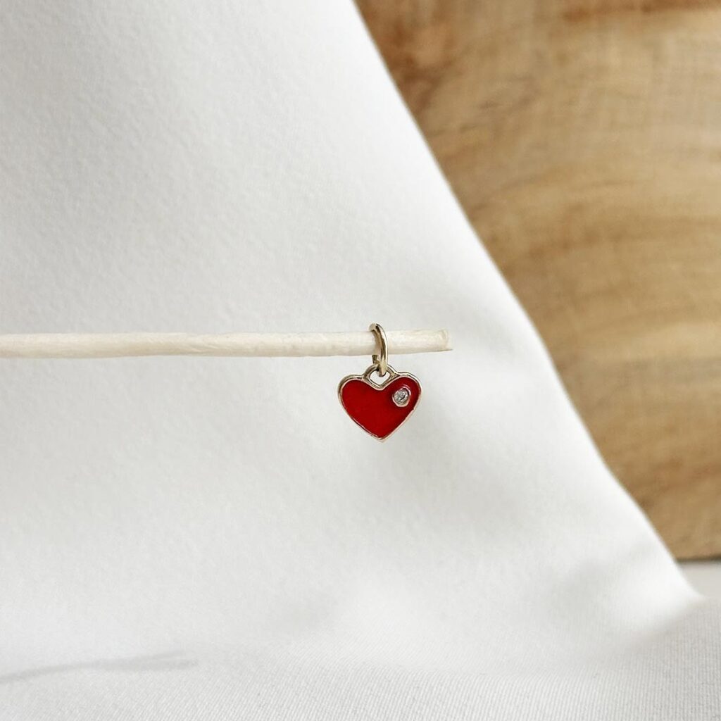 Kleiner Herzanhänger aus 585er Gelbgold mit rotem Lack und Zirkonia, elegante Nahaufnahme als Produktfoto.