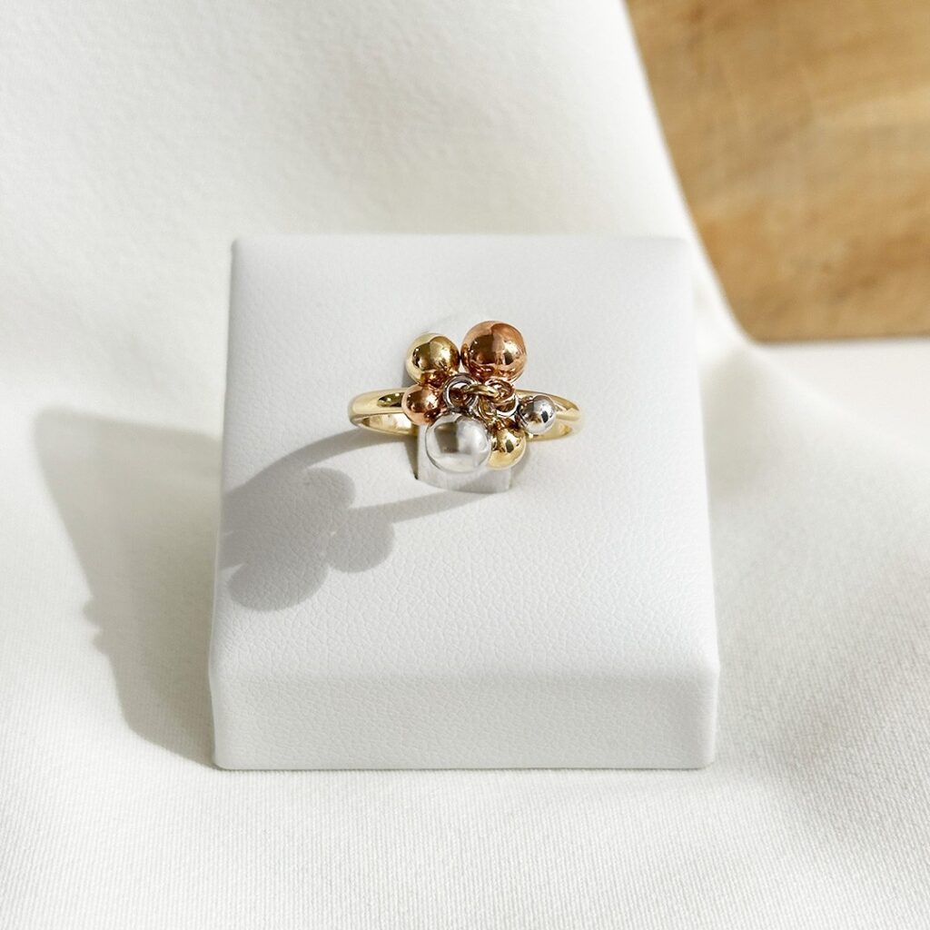 Ausgefallener Ring aus 585er Gelbgold mit Kugeln aus Gelb-, Weiß- und Rotgold, frontal in Nahaufnahme auf Ringaufsteller fotografiert, Fokus auf das verspielte Kugeldesign und den lebendigen Farbkontrast