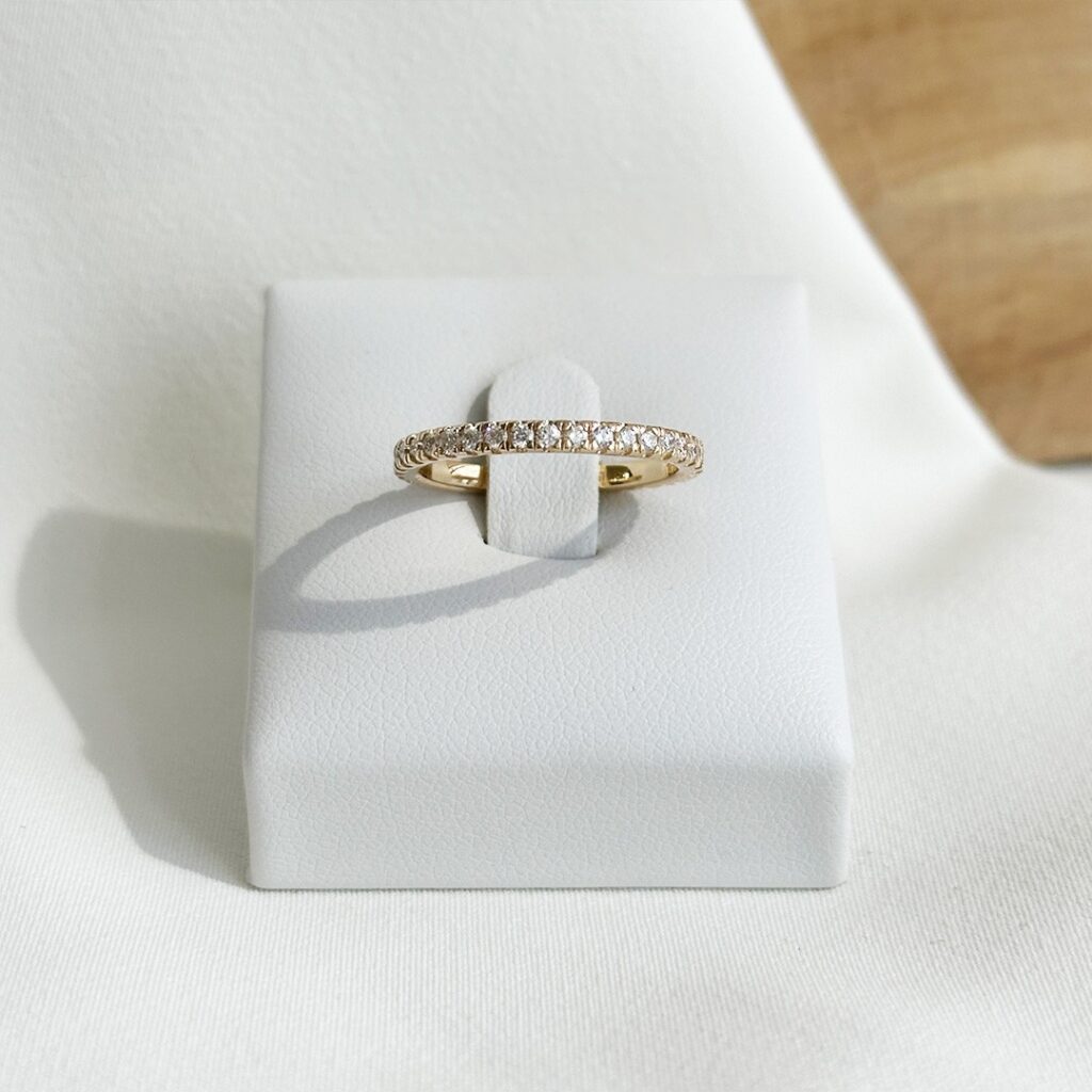 Memoiring aus 585er Gelbgold mit rundum gefassten Brillanten in Krappenfassung, frontal auf Ringaufsteller präsentiert, Fokus auf die gleichmäßige Steinreihe und die ruhige, zeitlose Brillanz