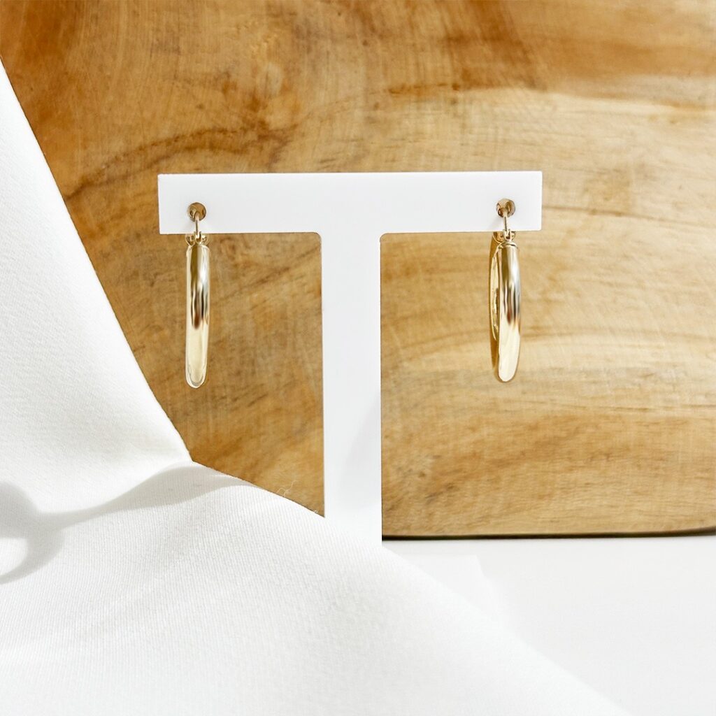 Klassische Creolen aus 585er Gelbgold mit 21mm Durchmesser, frontal auf Schmuckaufsteller fotografiert, Fokus auf die runde Form, die polierte Oberfläche und den warmen Goldglanz