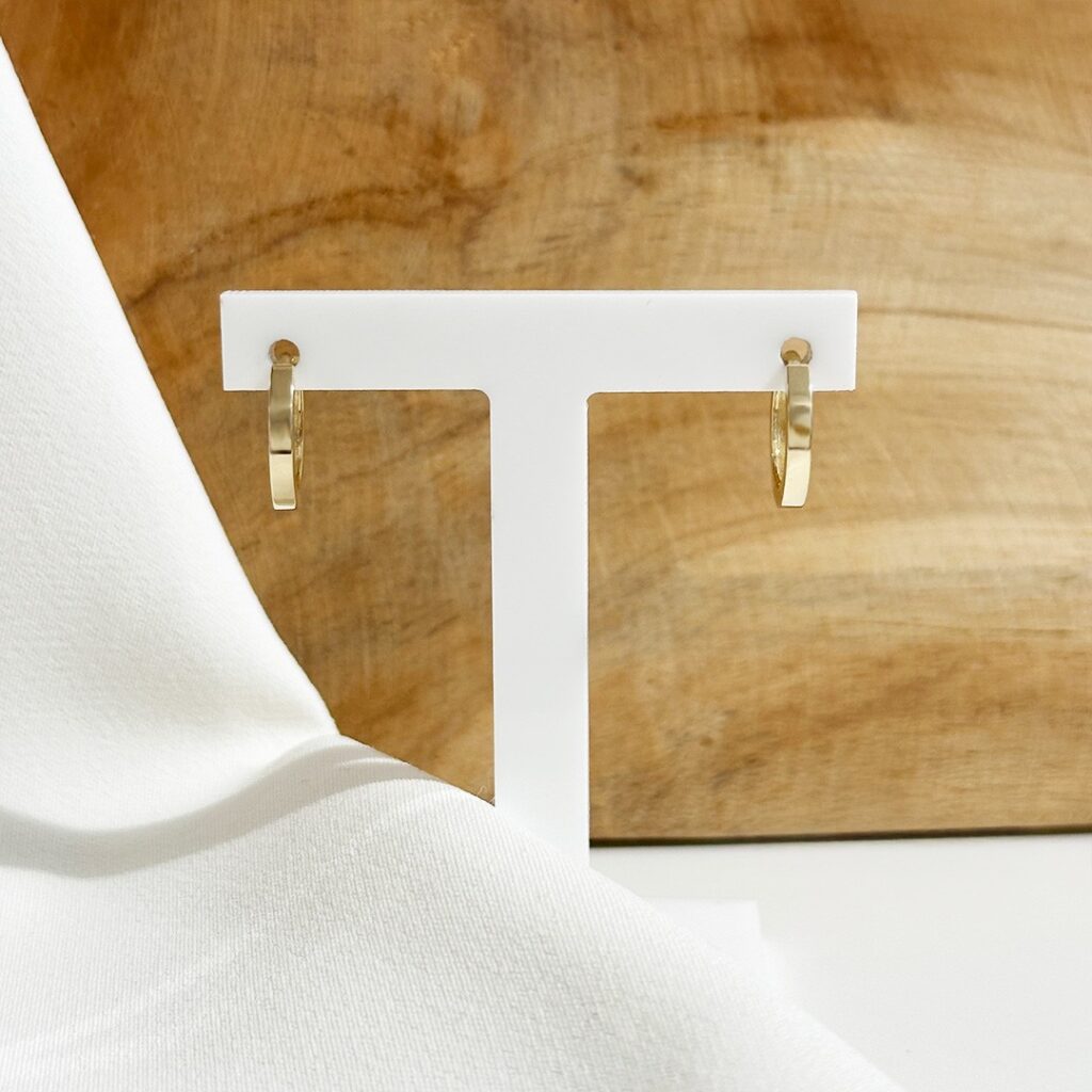 Kleine Creolen aus 585er Gelbgold mit ca.14mm Durchmesser, frontal fotografiert auf Schmuckaufsteller, Fokus auf die klare, geradlinige Form und die moderne, leicht eckige Anmutung