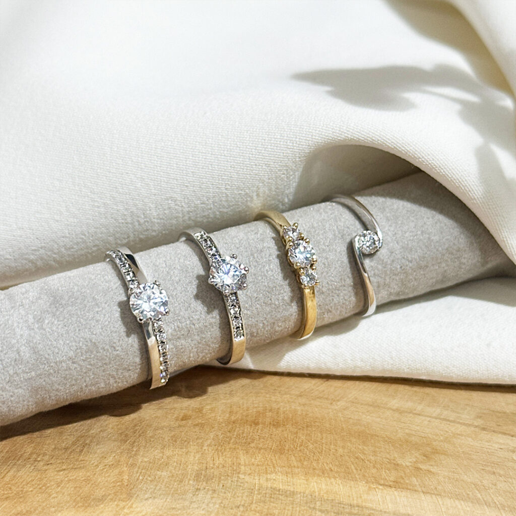 Individuelle Antragsringe Solitärringe aufgefädelt auf einer grauen Stoffrolle