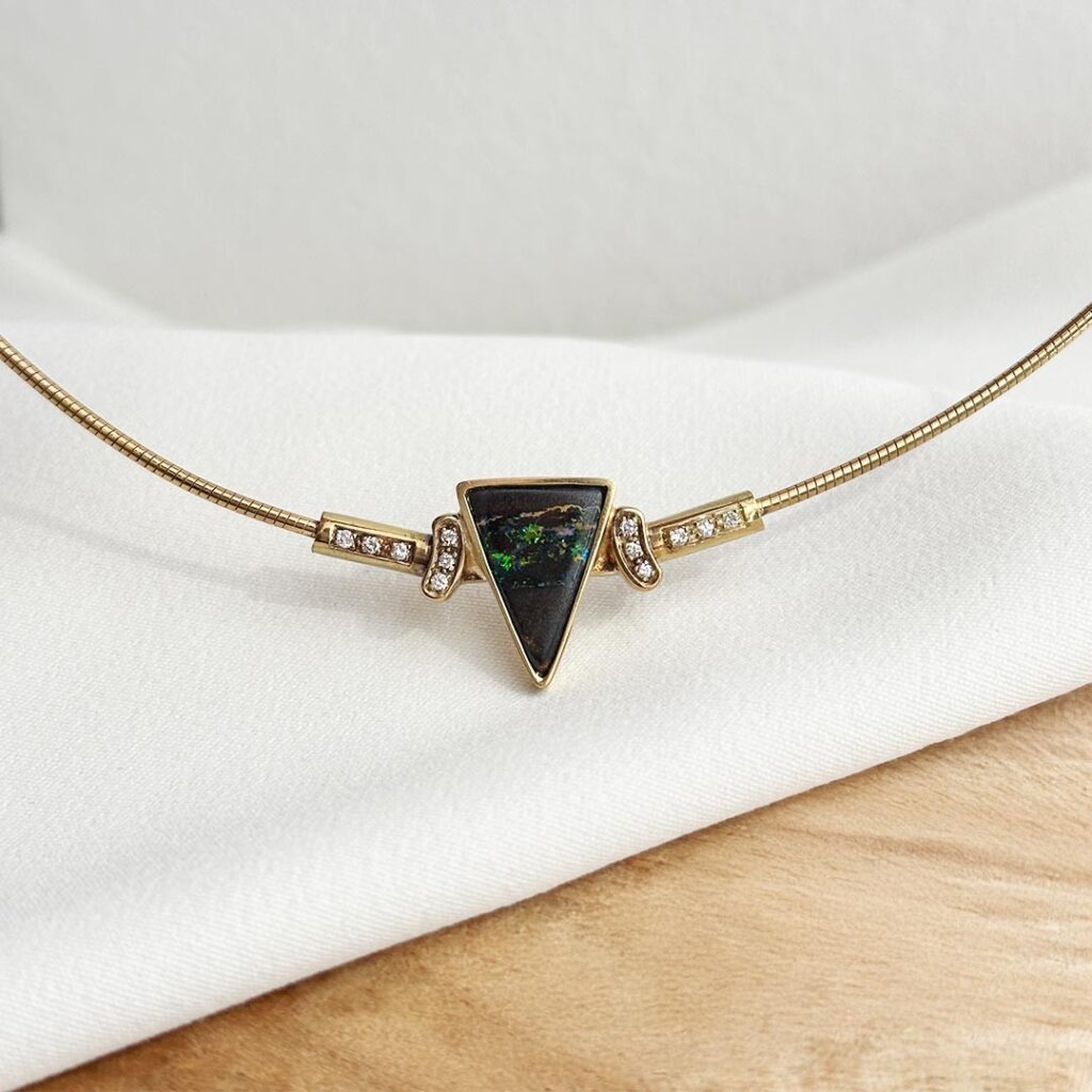 Collier aus 585er Gelbgold mit Opal und Brillanten, als Nahaufnahme fotografiert, Fokus auf den außergewöhnlichen dreieckigen Opal, die feinen Brillanten und das faszinierende Farbspiel des Edelsteins